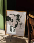 Art Print "Moo-tini" features a black and white cow with a martini glass. The martini glass has an olive skewer in it. 