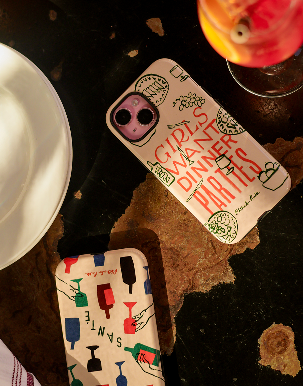 "Girls want dinner parties" printed on an iphone phone case next to an aperol spritz